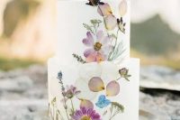 a fantastic wedding cake with white buttercream and white, lilac and pink pressed blooms and some herbs is ideal for a boho wedding