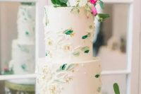 a fresh spring wedding cake with white sugar blooms and leaves painted, with gold foil and fresh greenery and blooms on top
