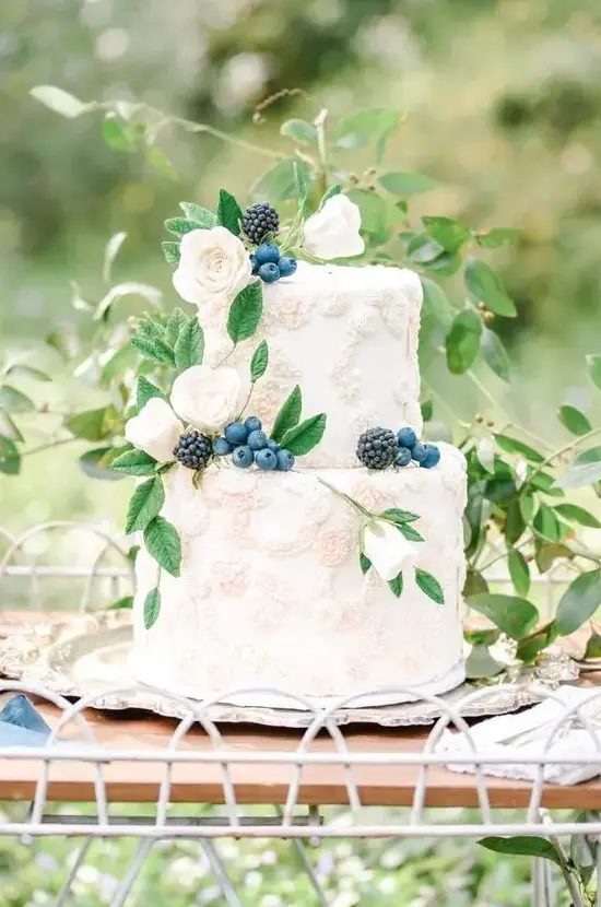 a heavenly secret garden wedding cake with sugar floral detailing, fresh berries and some foliage is a delicate and refined idea