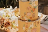 a honey yellow wedding cake with a rough edge, painted dimensional blooms and beads plus a cactus topper for a boho flower child wedding