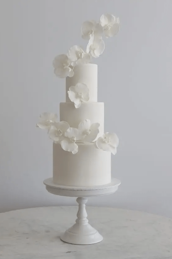 a minimalist white wedding cake decorated with white orchids is a very refined and chic idea for any minimalist wedding