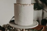 a minimalist yet glam textural neutral wedding cake decorated with a gold foil edge is a stylish idea for a minimal wedding