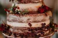 a naked chocolate wedding cake with berries, red blooms and greenery for a rustic winter wedding