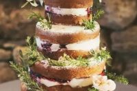 a naked wedding cake decorated with blueberries, fresh herbs and some blooms for a rustic feel