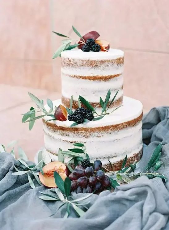 a naked wedding cake topped with greenery, peachies, grapes and blackberries is a cool summer and fall wedding