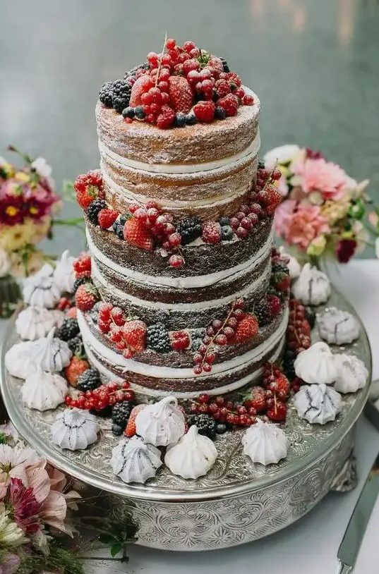 a naked wedding cake with lots of berries and meringues is a lovely idea for a rustic wedding