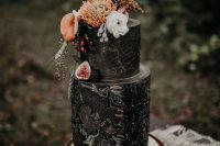 a painted black wedding cake with bold and neutral blooms, berries and antlers is a catchy and moody idea for a fall wedding