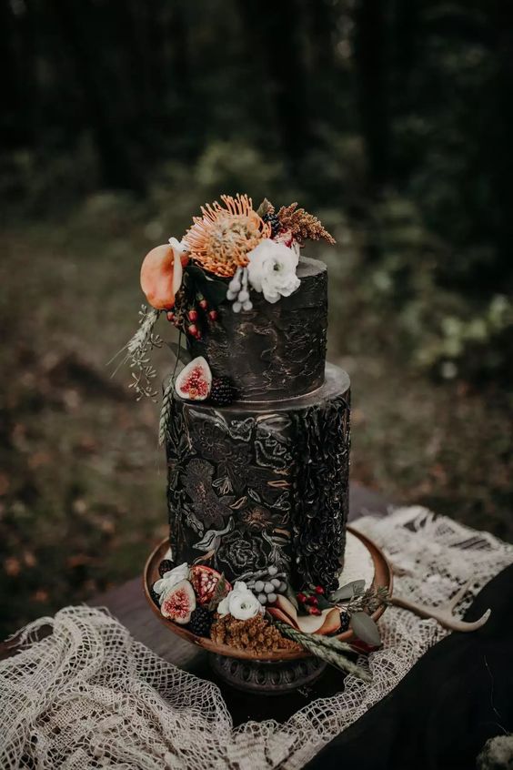 a painted black wedding cake with bold and neutral blooms, berries and antlers is a catchy and moody idea for a fall wedding