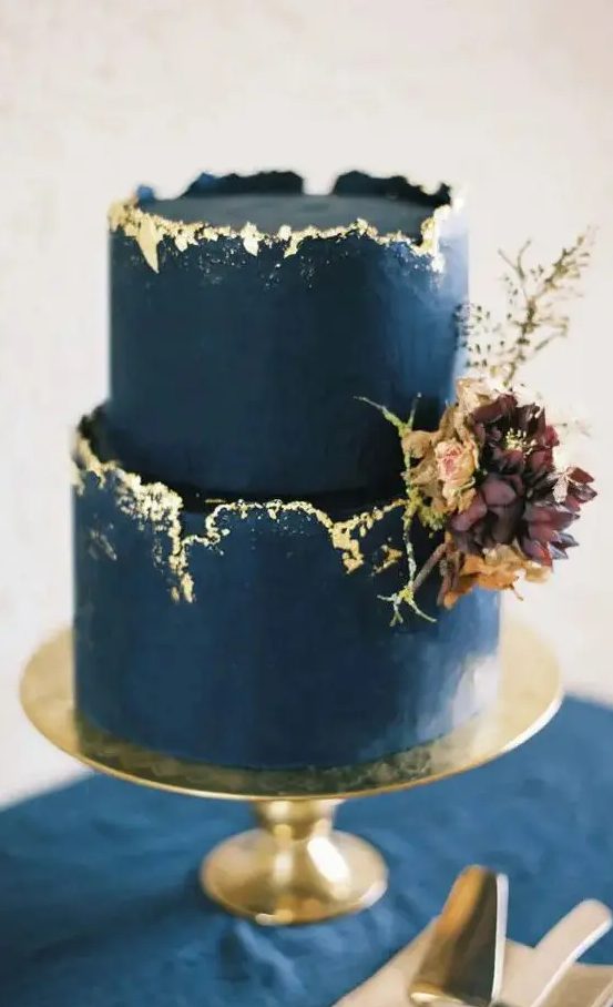 a refined and chic bold navy cake with a rough gold rim, with dark blooms and leaves is a very exquisite idea to go for
