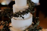 a sleek white wedding cake with eucalyptus spirals around looks jaw-dropping and will be a perfect match for a modern wedding