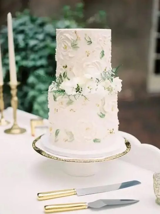 a sophisticated spring wedding cake in neutrals with sugar blooms and painted leaves, with fresh white flowers and ferns is amazing