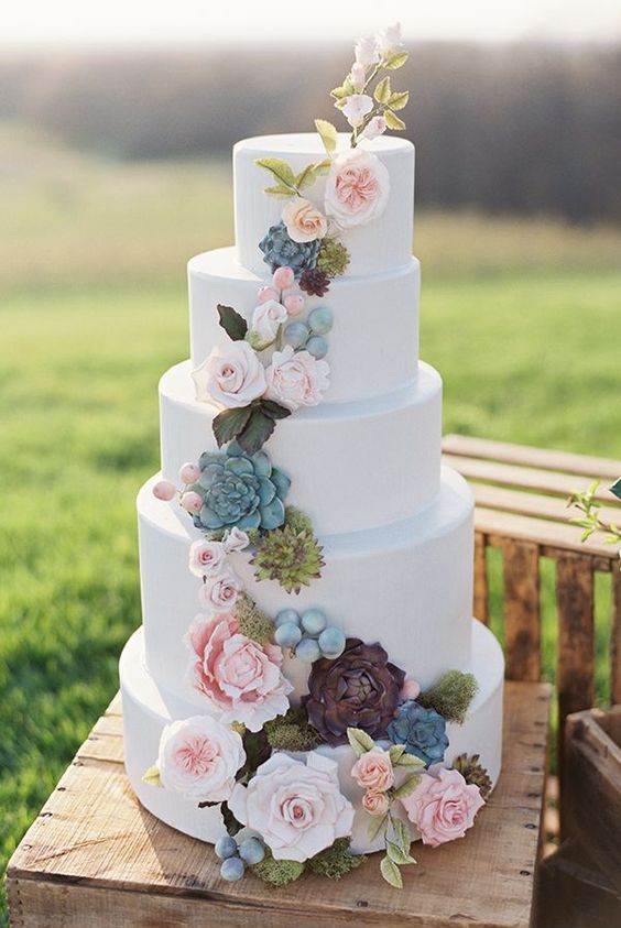 a stylish five tier wedding cake decorated with pink and dark fresh and sugar blooms, greenery, succulents and leaves and berries