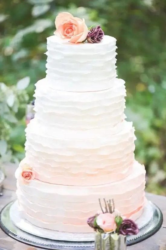 a subtle ombre ruffle wedding cake from white to blush and with peachy blooms is a cool idea for a spring or summer wedding