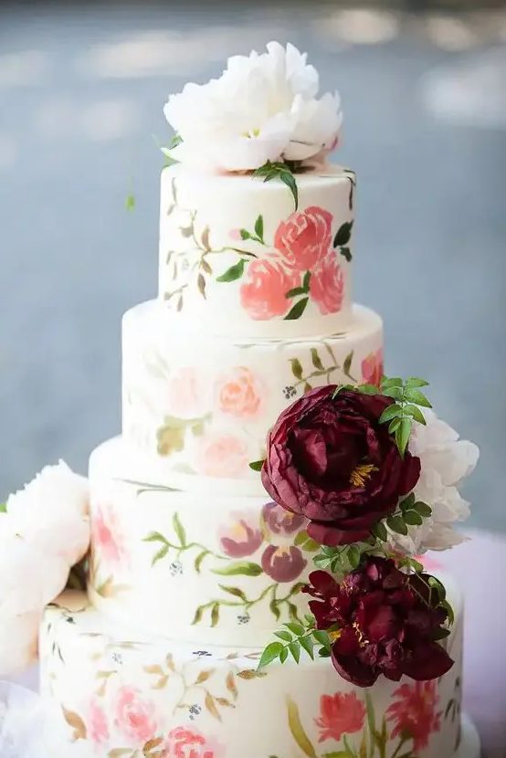 a sweet pastel handpainted wedding cake in various subtle shades with fresh blooms on top is ideal for summer
