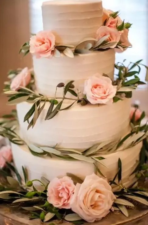 a tender white buttercream wedding cake decorated with greenery and blush roses is a beautiful idea for a spring or summer wedding