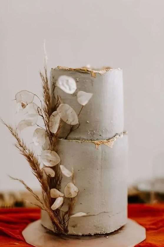 a textured grey wedding cake with a gold edge, dried grasses and lunaria is a stylish and catchy wedding cake