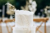 a white wedding cake with a ruffle edge and a touch of dried grasses is an airy and chic dessert for a minimalist fall wedding