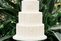 a white wedding cake with tiers decorated with patterns inspired by sweaters is a cozy and pretty solution for a winter wedding