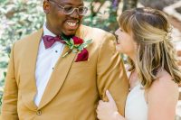 a bold groom’s look with a mustard blazer, black pants, a white shirt, a burgundy bow tie and a bold handkerchief