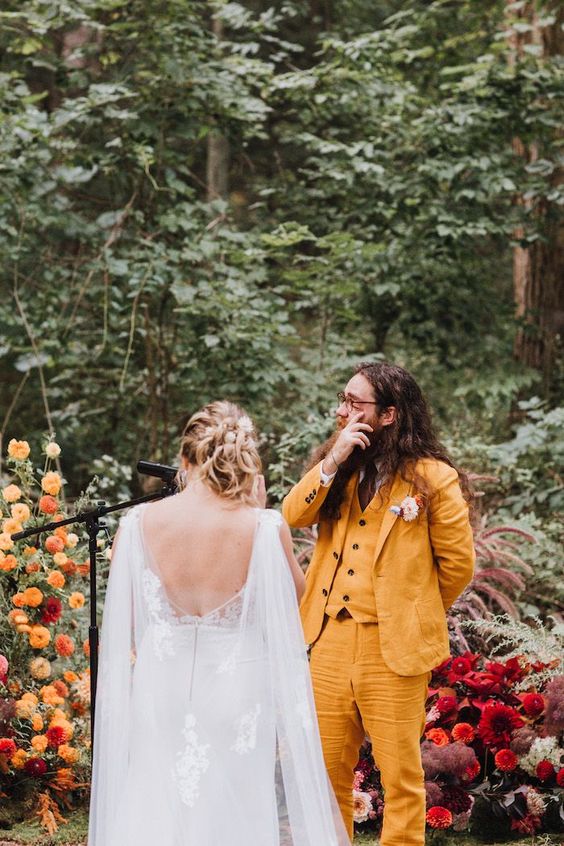a bold yellow three-piece suit, a white shirt, a brown tie and a dried flower boutonniere for a colorful wedding