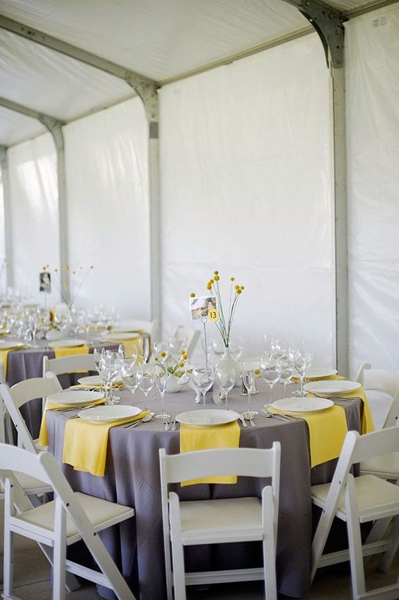 a bright and simple wedding tablescape with a grey tablecloth, yellow npakins, neutral porcelain and billy balls
