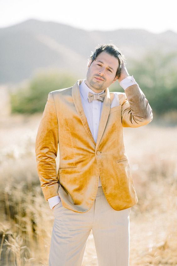 a catchy groom's look with a white shirt, a msutard velvet blazer, grey pants and a white shirt for the fall