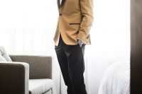 a catchy groom’s look with a white shirt, a mustard tuxedo with black lapels, a black bow tie, black trousers and shoes