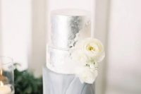 a chic silver leaf, white and grey marble wedding cake decorated with white ranunculus is a stylish and romantic idea for a modern wedding