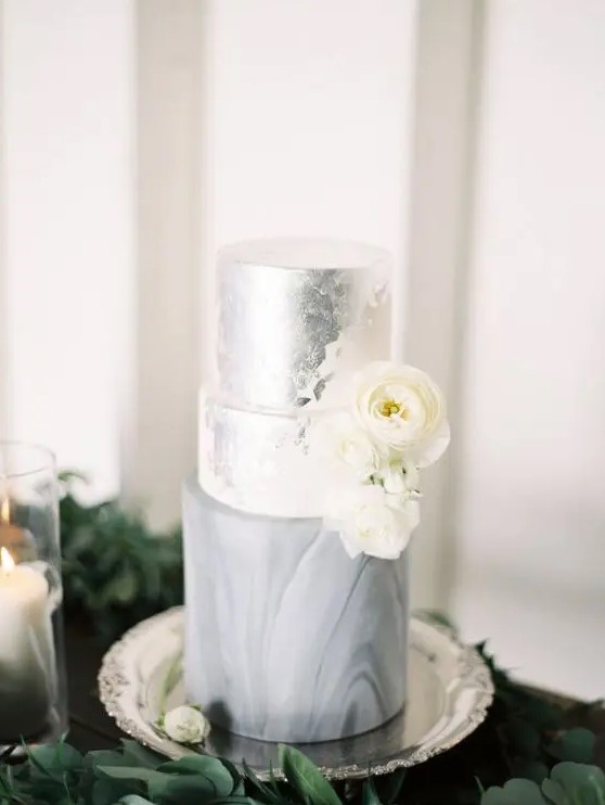 a chic silver leaf, white and grey marble wedding cake decorated with white ranunculus is a stylish and romantic idea for a modern wedding