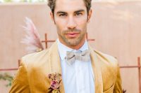 a glam groom’s look with a white shirt, a grey bow tie, a mustard velvet blazer and a pink boutonniere for a glam wedding