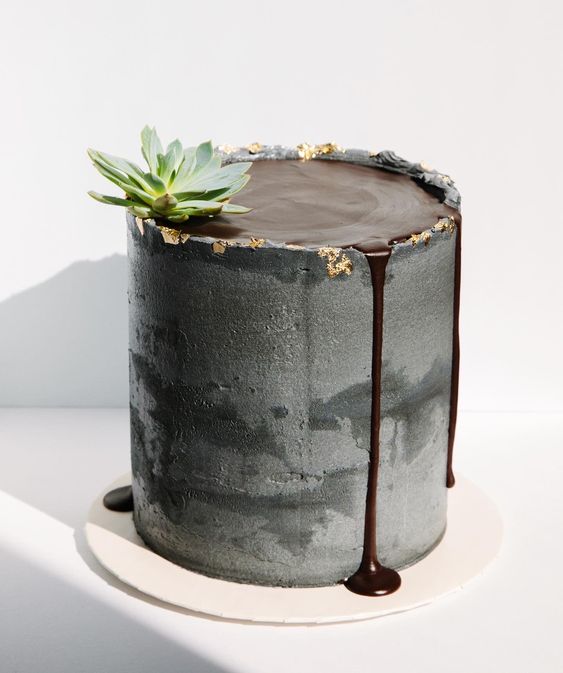 a grey concrete wedding cake with chocolate on top and some chocolate drip, a succulent for a modern wedding