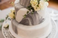 a grey marble and white wedding cake topped with white blooms and greenery for a chic and refined modern wedding