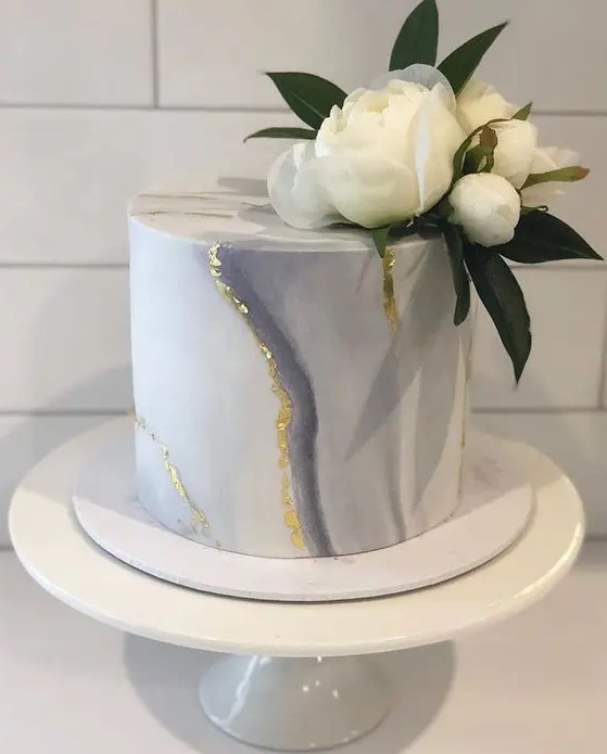 a grey marble mini cake with gold leaf and fresh white blooms and leaves is an elegant and chic idea