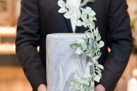 a grey marble wedding cake decorated with greenery is a super stylish, bold and catchy wedding dessert
