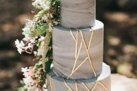 a grey marbleized cake decorated with gold geometric touches and cascading greenery and blooms