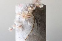 a grey textured wedding cake with gold touches and some blush blooms for a creative modern wedding