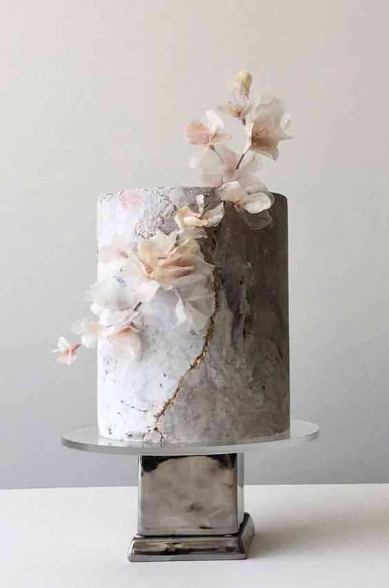 a grey textured wedding cake with gold touches and some blush blooms for a creative modern wedding