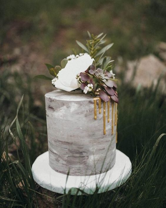 a grey watercolor wedding cake with gold drip, white blooms and green and purple succulents for a modern wedding