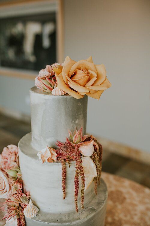 a grey wedding cake topped with pink, orange blooms and amaranthus for a modern wedding with a bold color scheme