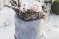 a grey wedding cake with white and pink blooms, driftwood, grasses and berries for a modern coastal wedding