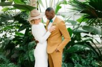 a groom wearing a mustard suit, a white shirt, a green bow tie and brown shoes looks super chic