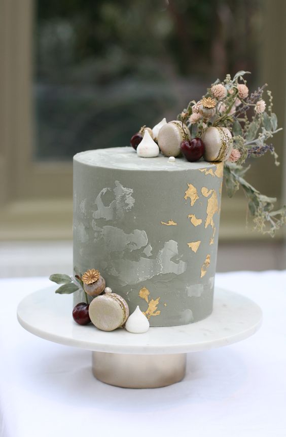 a matte grey wedding cake with gold foil, macarons, meringues and greenery and seed pods for a modern wedding
