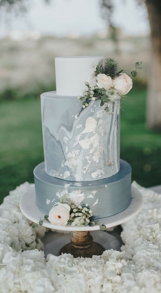 a modern wedding cake with a grey, white and grey marble tier, gold foil, neutral blooms and greenery is a stylish idea
