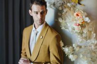 a mustard suit, a white shirt, a grey tie are a cool combo for a modern groom who wants some color