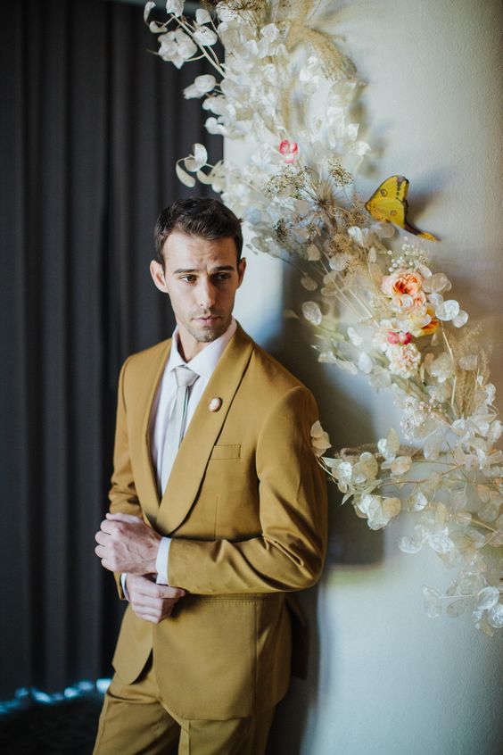 a mustard suit, a white shirt, a grey tie are a cool combo for a modern groom who wants some color