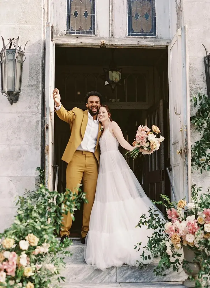 a mustard suit, a white shirt, black shoes and a boutonniere are a cool combo for a modern groom