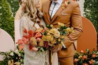 a mustard three-piece suit, a white shirt, a bolo tie, a yellow floral boutonniere for a boho groom’s look