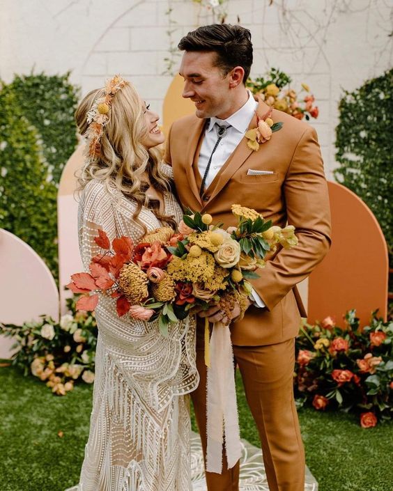 A mustard three piece suit, a white shirt, a bolo tie, a yellow floral boutonniere for a boho groom's look