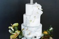 a neutral marble wedding cake decorated with candles and white orchids plus fresh blooms and succulents around is a refined out of the box idea