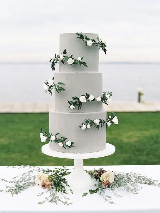 a plain grey wedding cake with white blooms and greenery is a chic and modern idea with a touch of romance